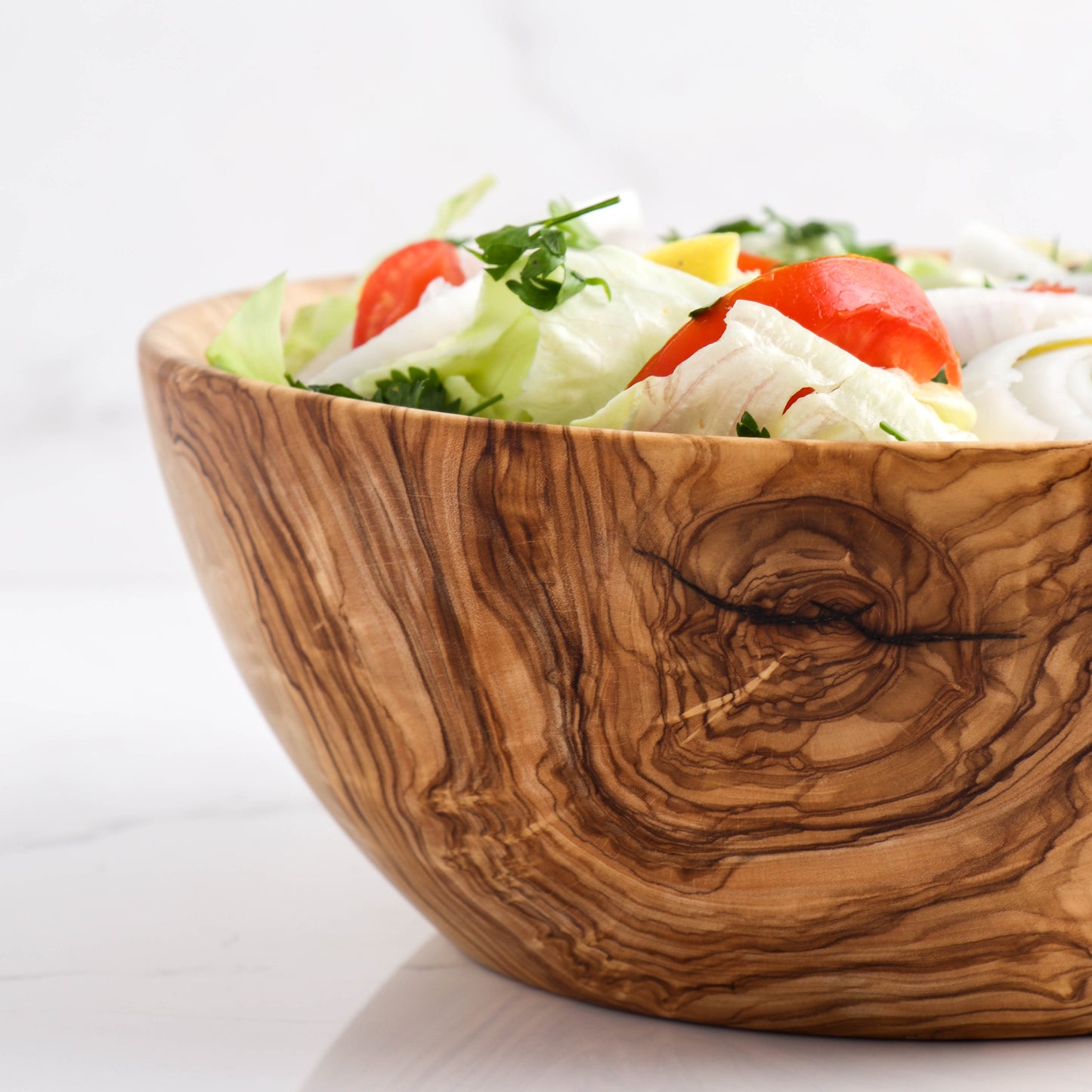 Handmade Olive Wood Salad Bowl: A generously sized, durable bowl for gatherings, featuring the distinctive, swirling grains of olive wood, each piece one-of-a-kind, marrying beauty with practicality
