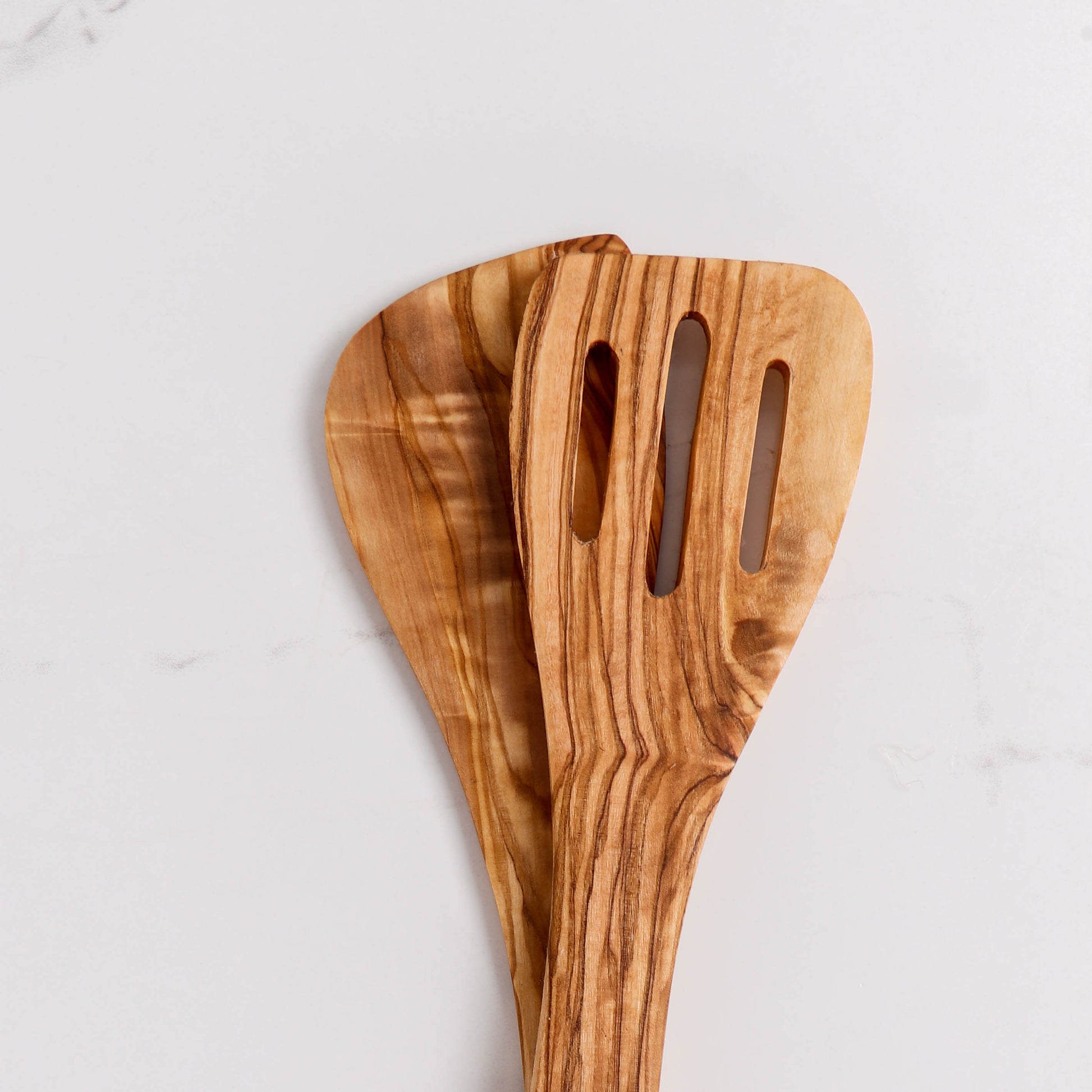Durable Olive Wood Cooking Utensil: Slotted Spatula. Each piece is hand-carved, showcasing unique grain patterns. Perfect for everyday cooking, this wooden spatula combines style with function, making it a must-have for culinary enthusiasts.