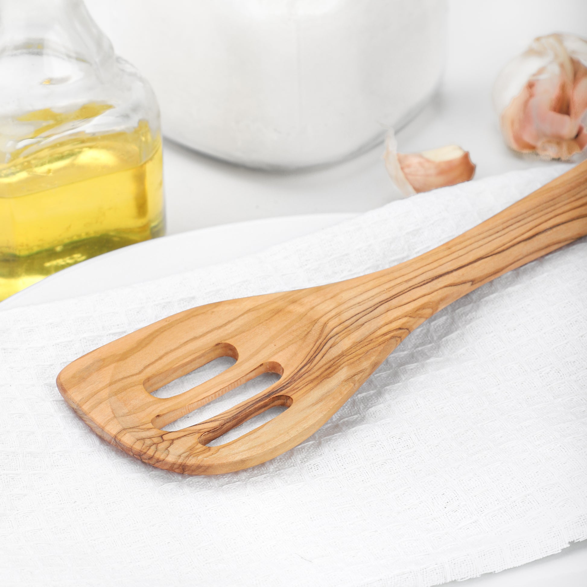 Elegant Olive Wood Cooking Utensil: A slotted spatula designed for everyday culinary tasks. Its strength and beautiful grain make it an essential kitchen piece for those who appreciate quality and durability in their cooking tools