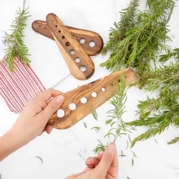 Artisan Olive Wood Herb Stripping Tool with 8 multi-sized holes, perfectly sized at 7.5", featuring a handcrafted design with unique grain details, lying against a white backdrop, illustrating its practical use and beauty.